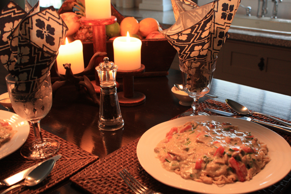 diner setting with pasta and mushroom sauce, wine glasses, and candles